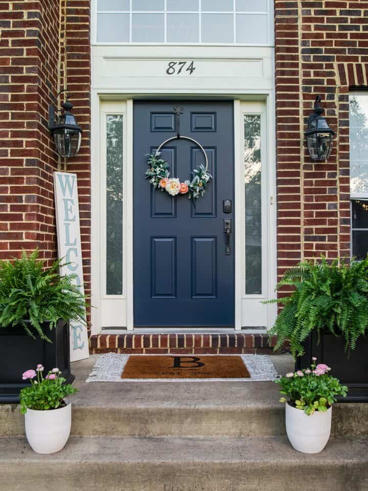Blue front door on red brick house with planters on either side.