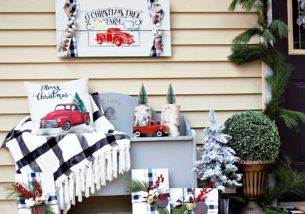 Red truck themed Christmas decoration on a bench with presents and a plaid blanket.