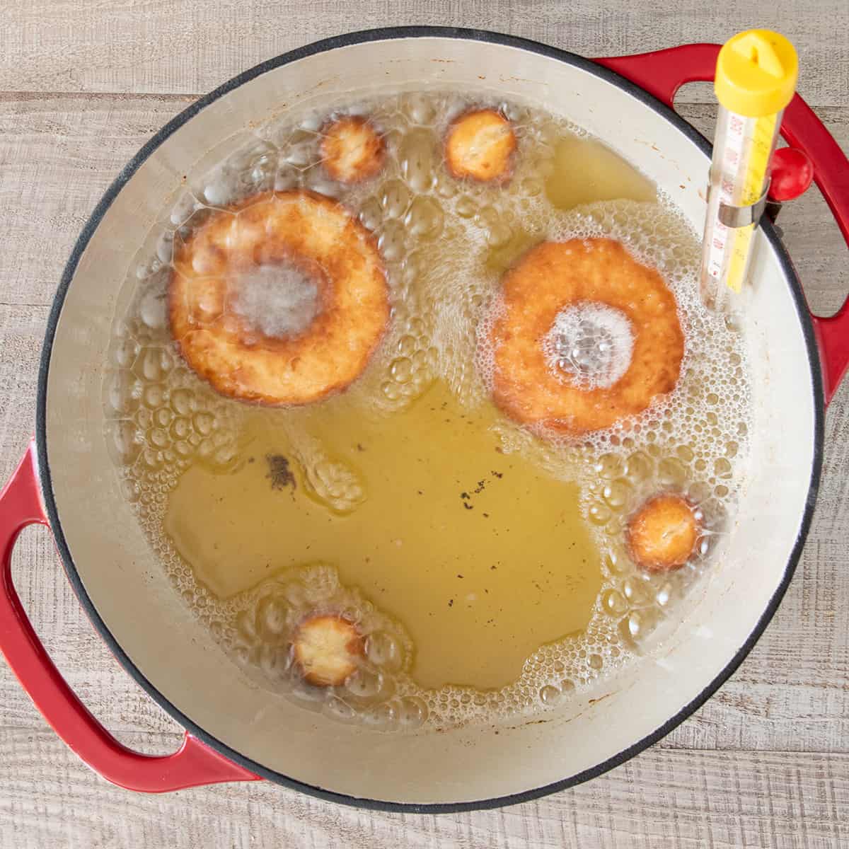 Overhead of donuts frying in a dutch oven of vegetable oil.