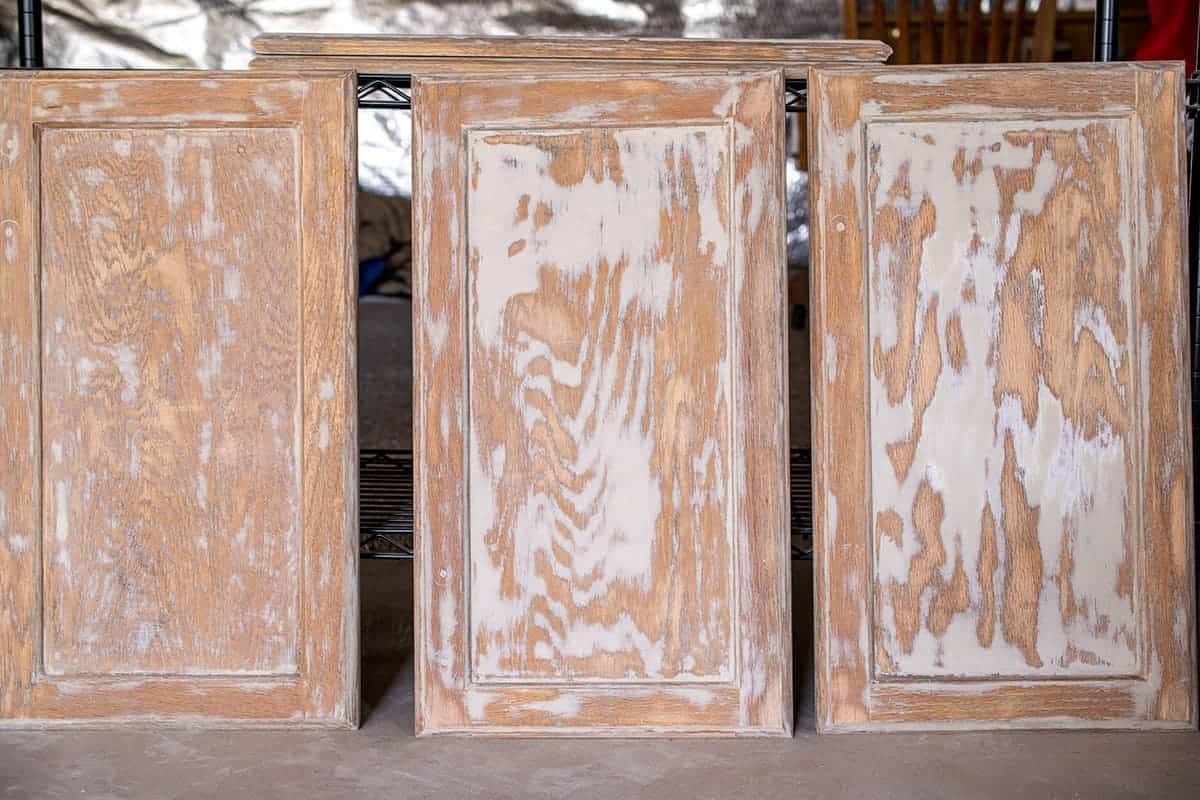 Three cabinet doors upright after sanding and filling wood grain.