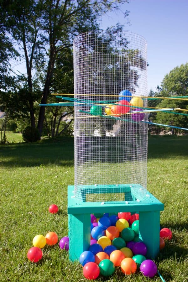 Giant Kerplunk with colorful "ballpit" style balls in a park-like grassy area.