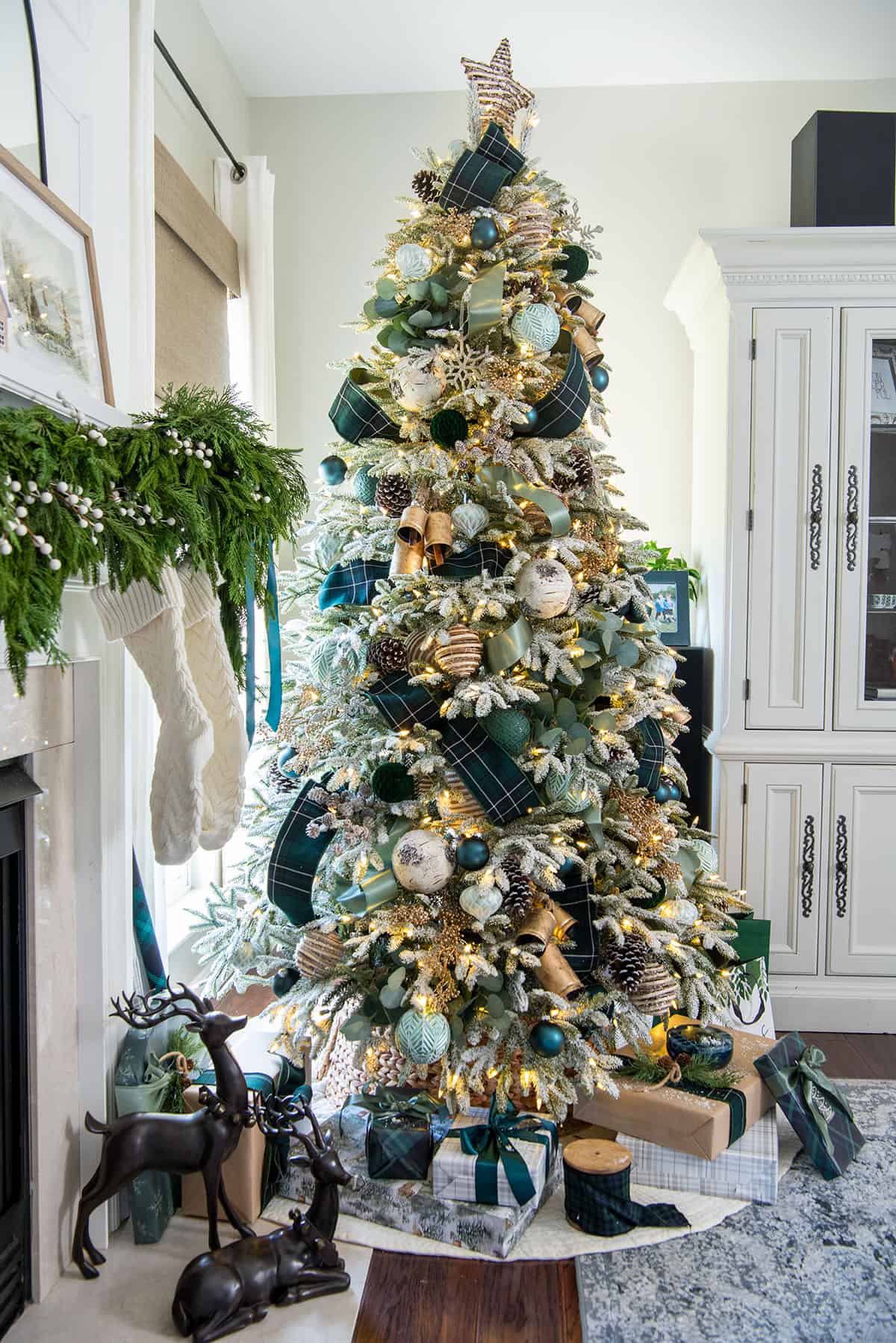 Green Christmas tree color scheme decorations on a lighted holiday tree with dark green tartan ribbon and brass bells and green ornaments.