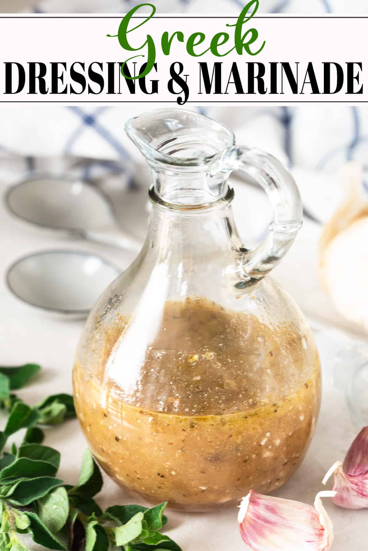 A bottle of Greek salad dressing in a bottle with Mediterranean spices an spoons around it.