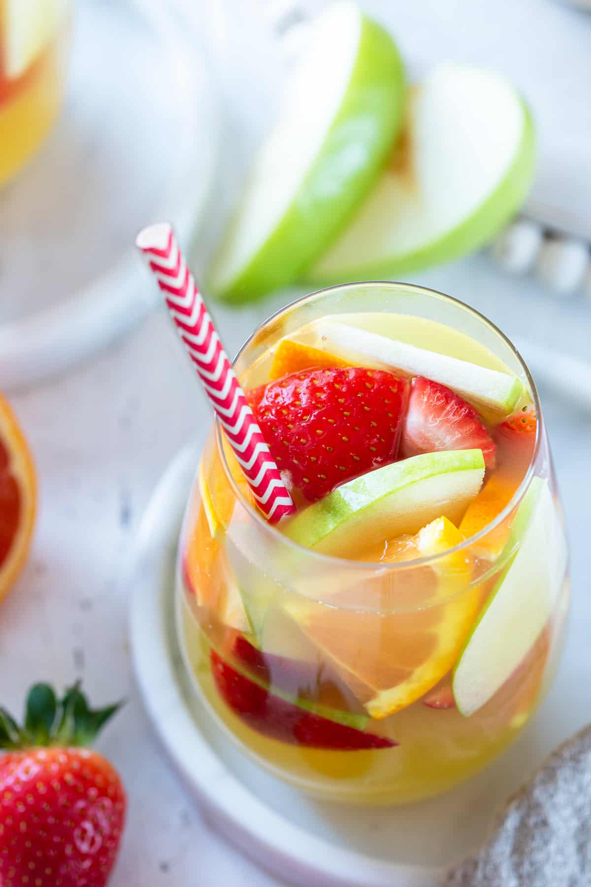 Overhead of a glass of Olive Garden copycat green apple sangria with apple, orange, and strawberry slices in it.