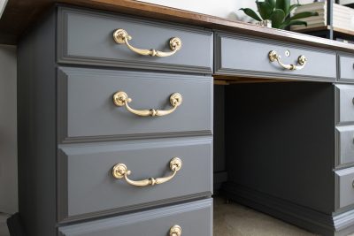 Grey desk with brass handles up close.