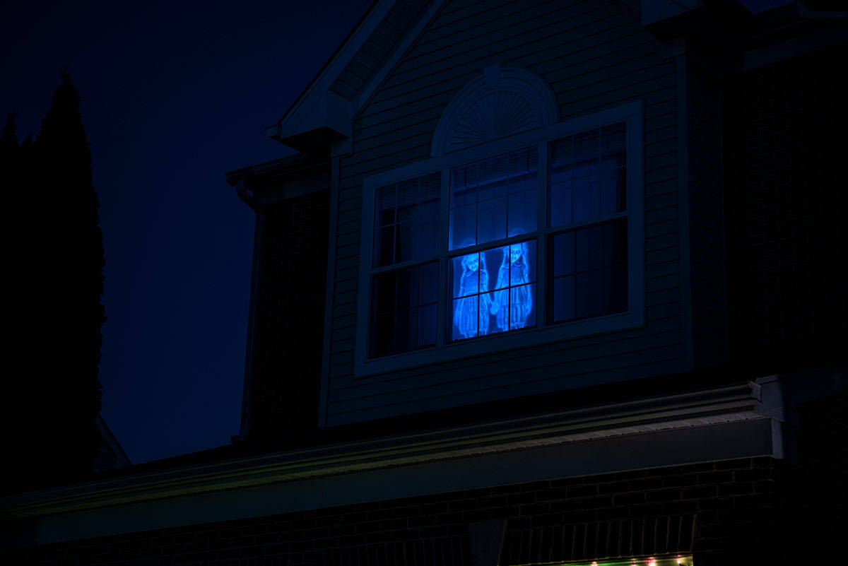 Looking up to a Halloween digital decoration in a window at night.