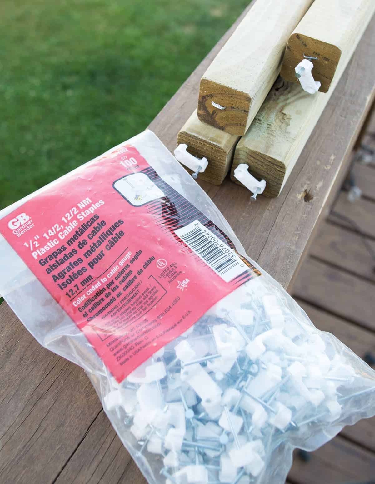 Bag of plastic cable staples on top of wooden handrail on outdoor deck.