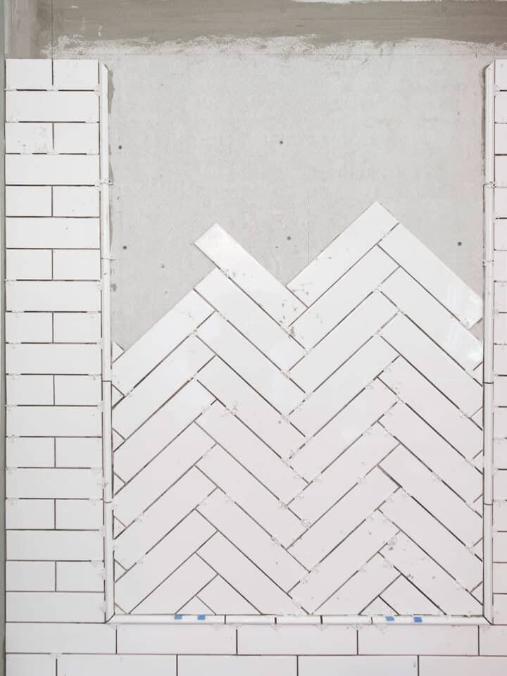 Herringbone pattern tile on a wall during installation.