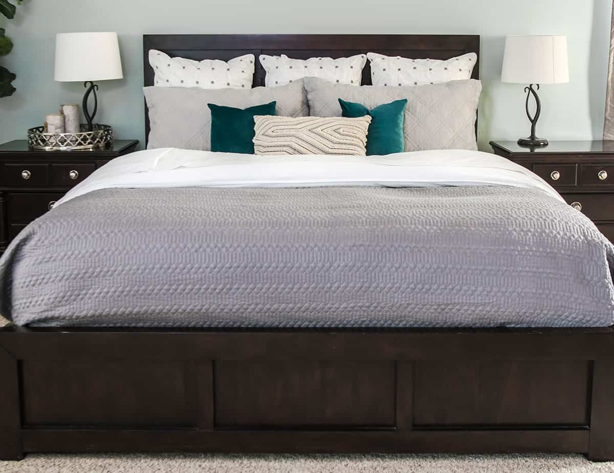 How to Make a beautiful bed final with Gray quilt, decorative throw pillows, shams, white sheets down turned.