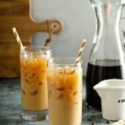 Glasses of Mixed Iced Latte Coffees with carafe and golden straws in the beverages.
