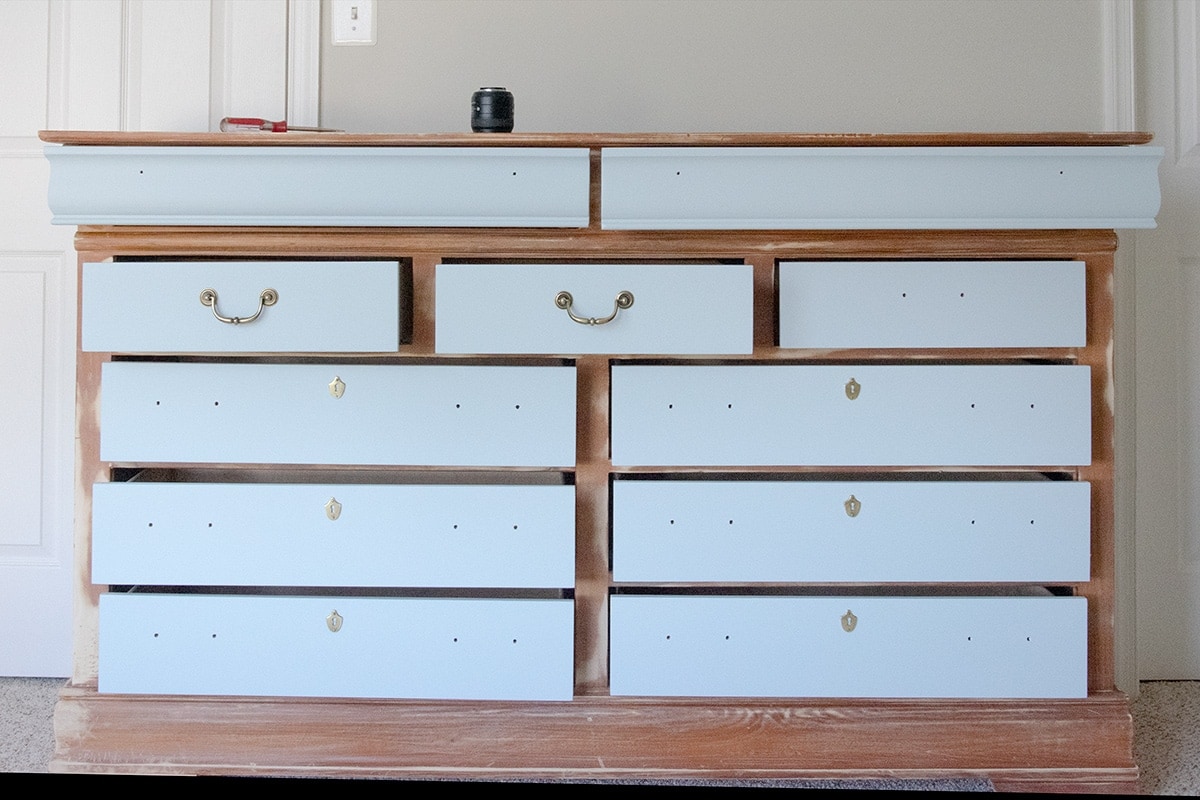 The front of a dresser with drawers pulled out and painted to allow them to dry.