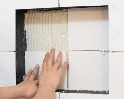 Laying tile in a shower wall niche.