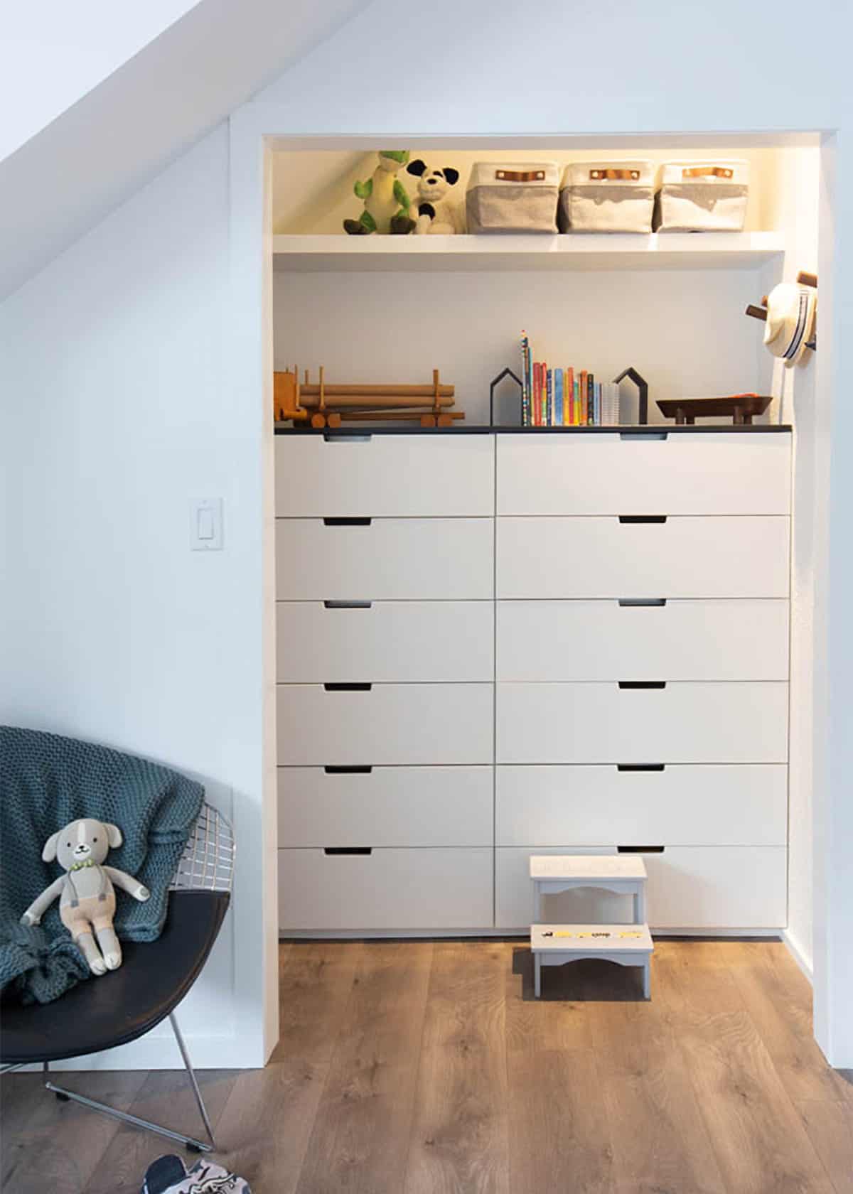 A white closet with a white IKEA dresser and a shelf up top with baskets.