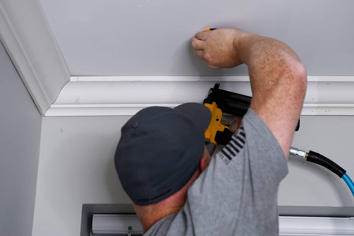 Man installing crown molding using a brad nailer.