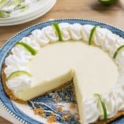 Key lime pie on blue plate with a slice cut out to show texture.