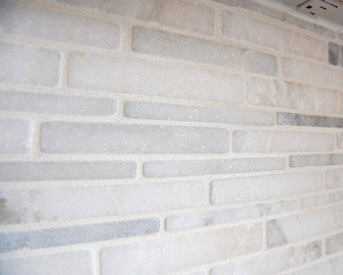 Closeup of sanded grout in between honed marble tiles.