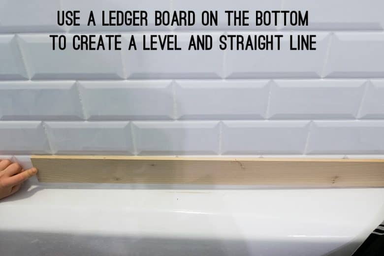 A ledger board being held up for tiling a wall.