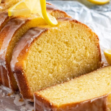 Sliced lemon yogurt cake with glaze and lemon curl slices on top.