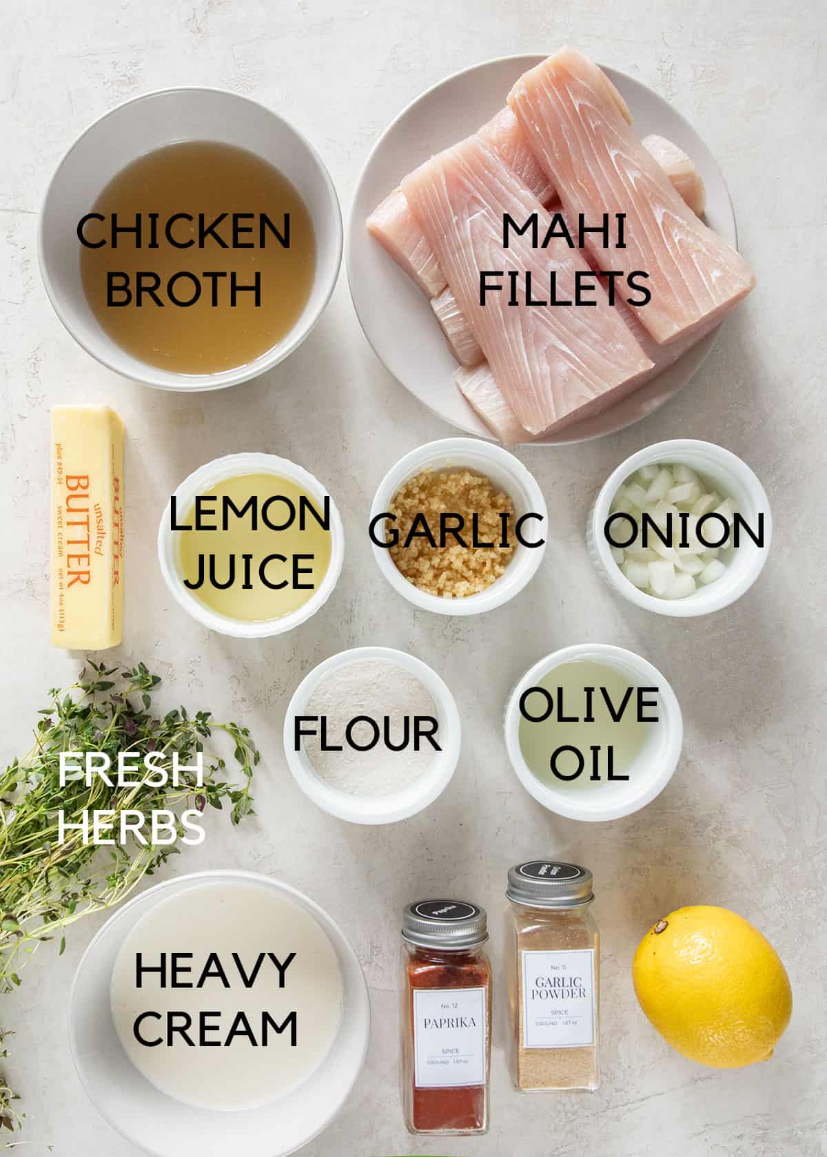 Ingredients to make mahi mahi with garlic cream sauce and fresh herbs laid on a table.