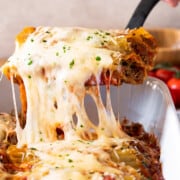 Beef Cannelloni being pulled out of pan with melted mozzarella cheese stringing.