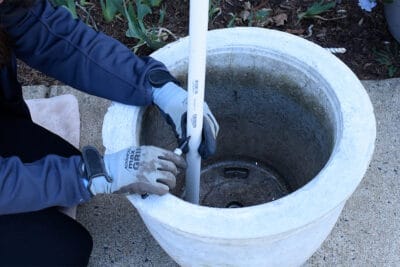 Woman marking a pvc pipe for cutting at the height of a planter.