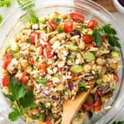 Overhead view of Mediterranean orzo mixture in a glass bowl with feta and parseley sprinkled over top.