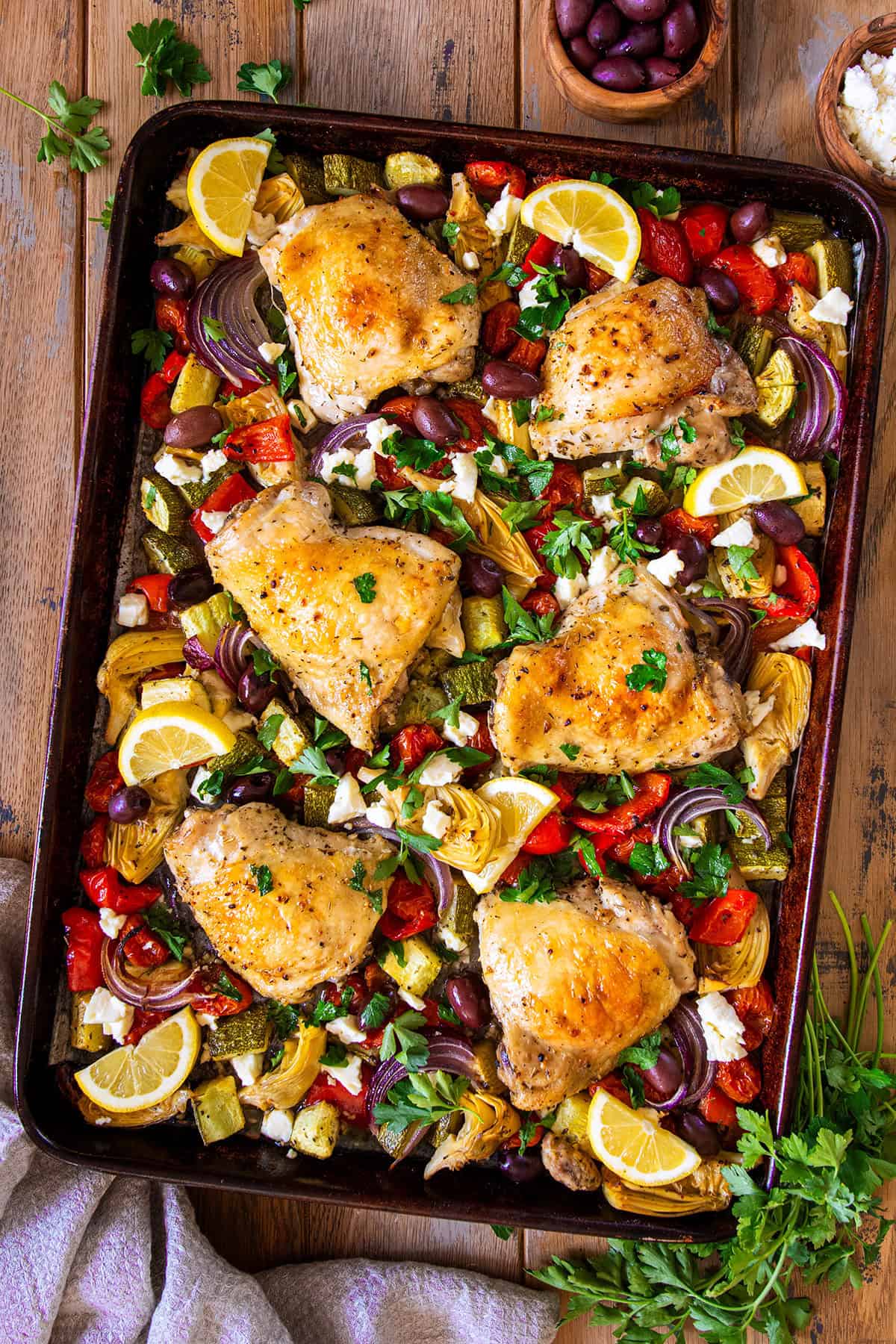 Overhead of chicken and Greek vegetables laid out on a sheet pan after baking.