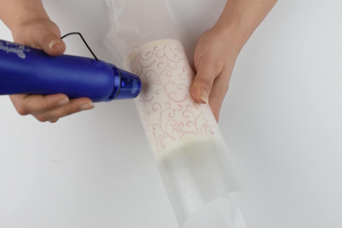 I'm using a blue heat gun over the surface of the wax paper wrapped candle.