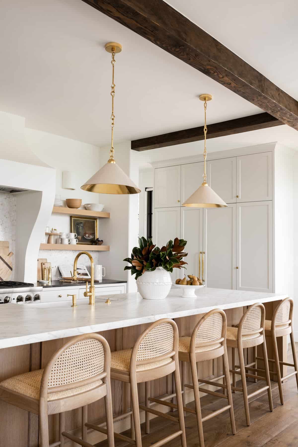 Neutral kitchen with warm natural wood. White oak cabinets, black and white marble counters and brass pendant lighting.