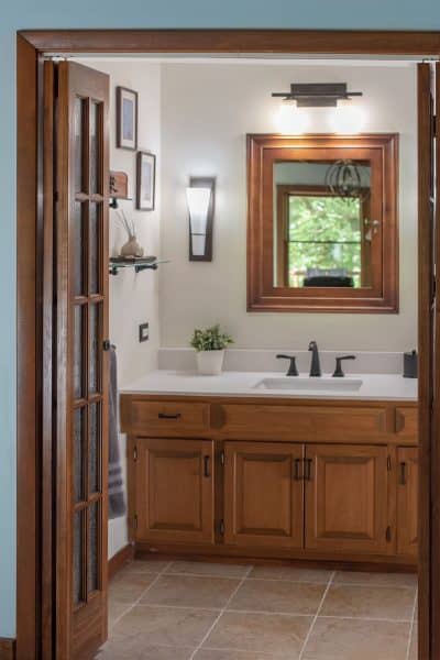 Rustic bathroom with wood vanity, mirror and doors.