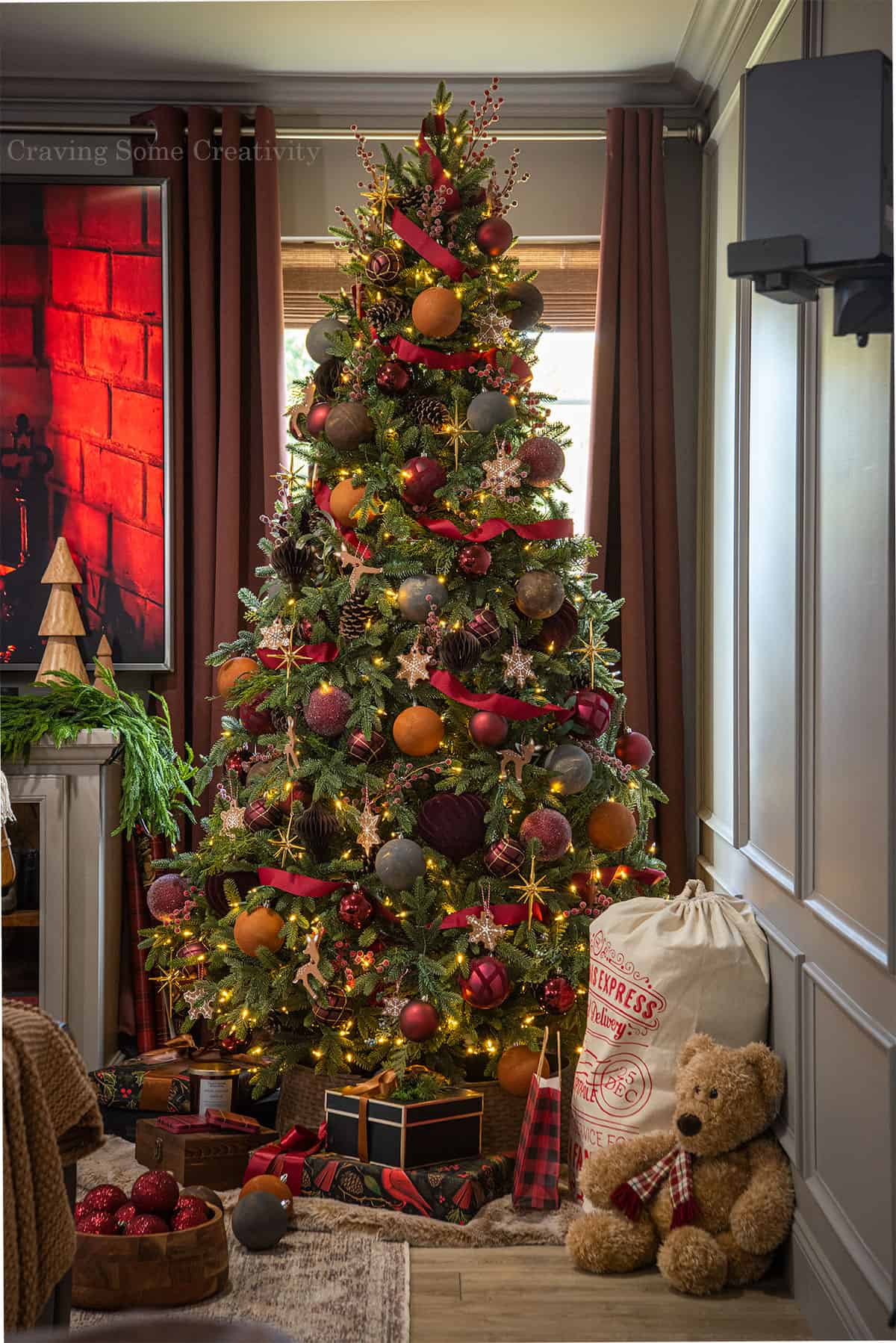 A Charles Dickens inspired Christmas tree with brown, rust, and red color scheme surrounded by antiques and gifts.