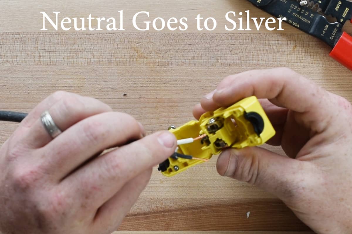 Closeup of putting a neutral wire into a silver terminal pinch point.