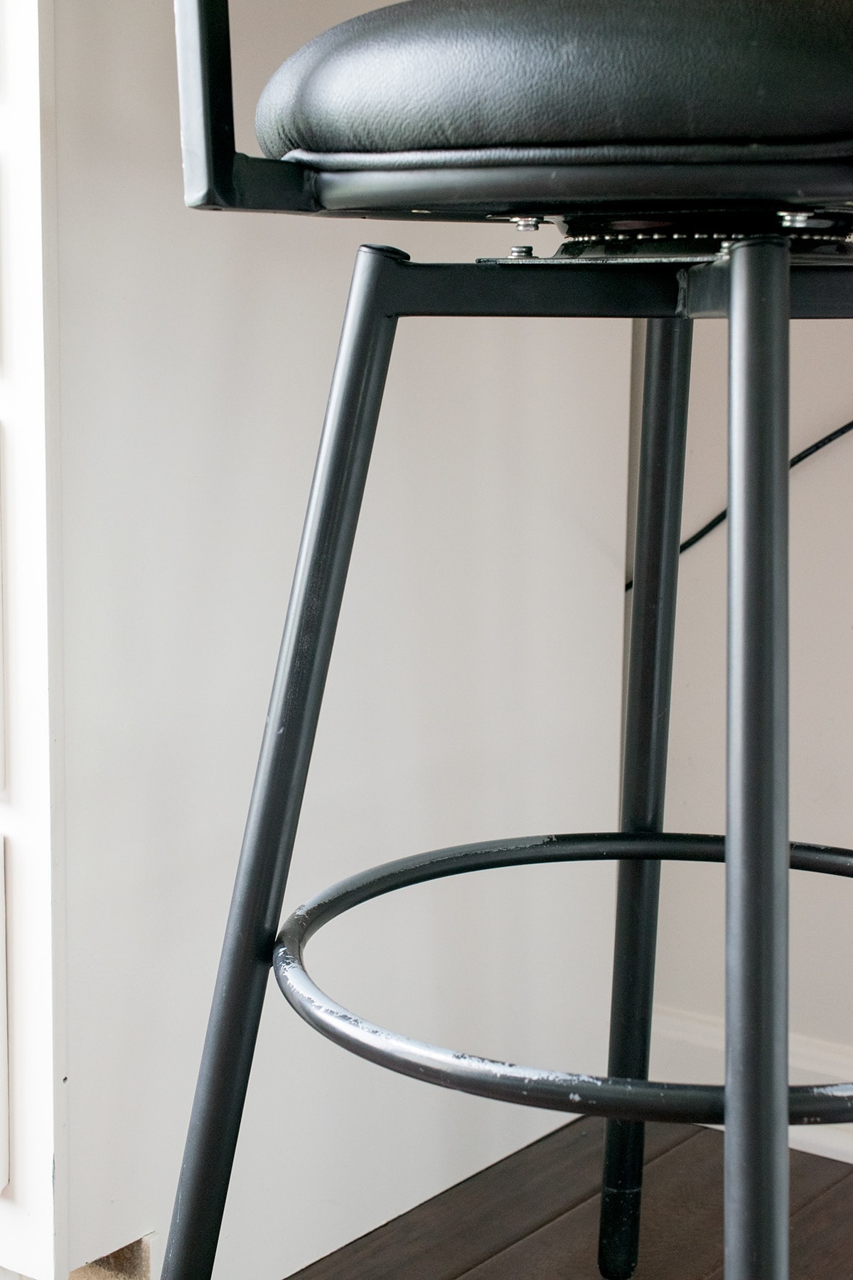 Black base on tall office chair with chipped paint on foot rail