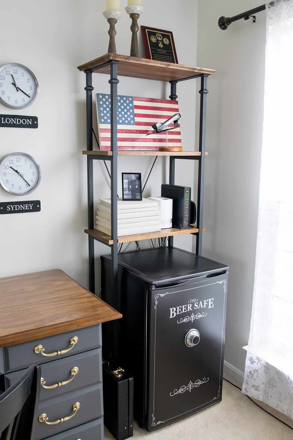 Industrial looking wood and black metal office shelf with patriotic pictures and decor with safe inspired mini fridge underneath