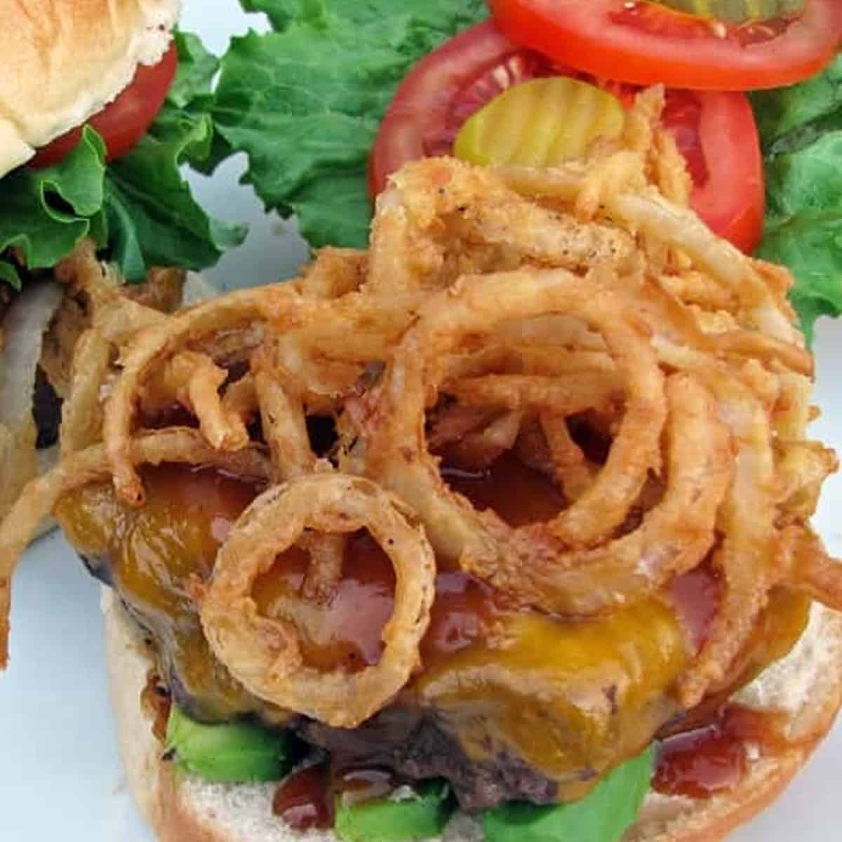 Golden onion straws or thin rings laid atop a hamburger.