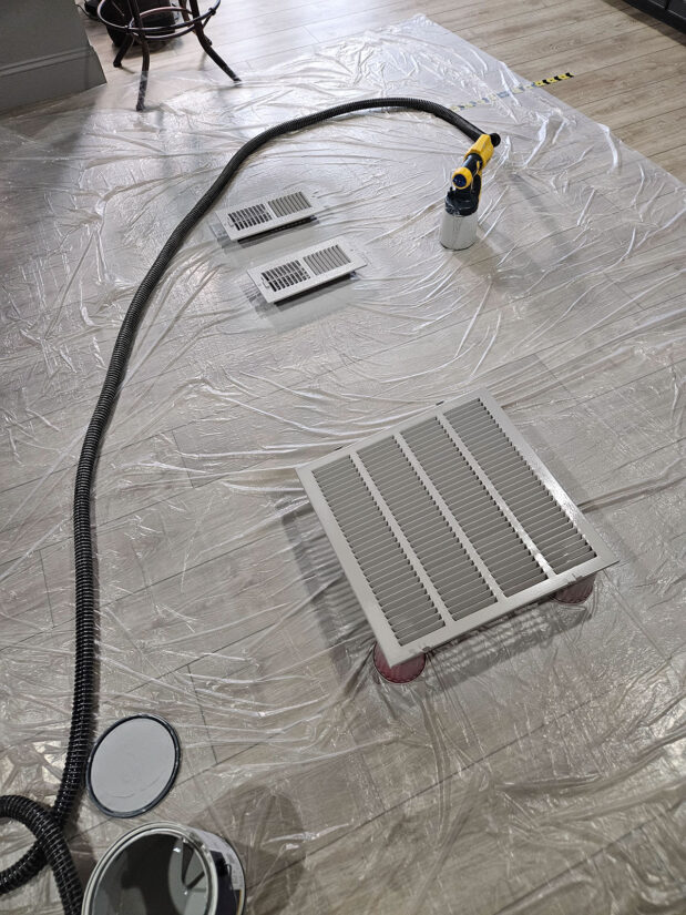 Air return and vent grates setup on the floor for spray painting.