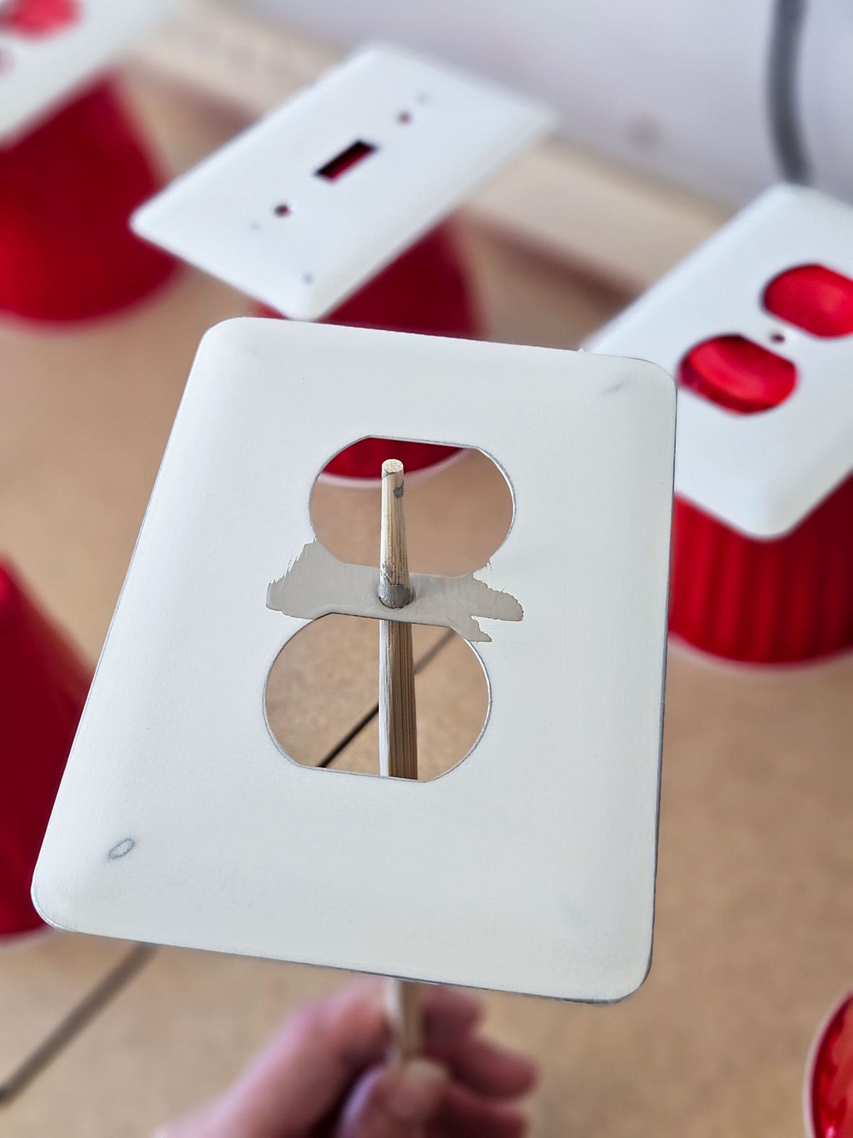 A outlet cover on a bamboo chop stick in order to not touch the wet paint.