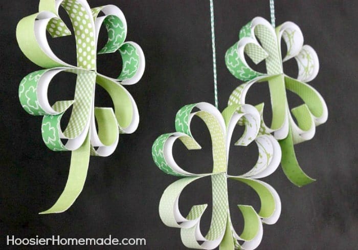 Hanging Paper Shamrocks made of decorative green craft papers with black background.