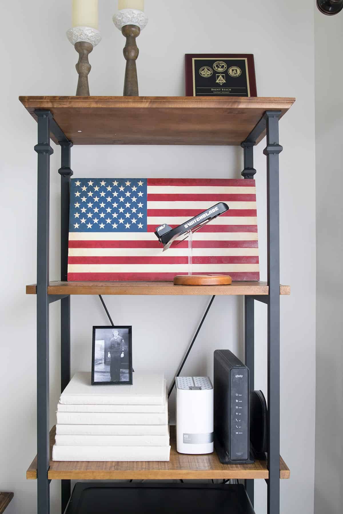 Industrial looking wood and black metal office shelf with patriotic pictures and decor.