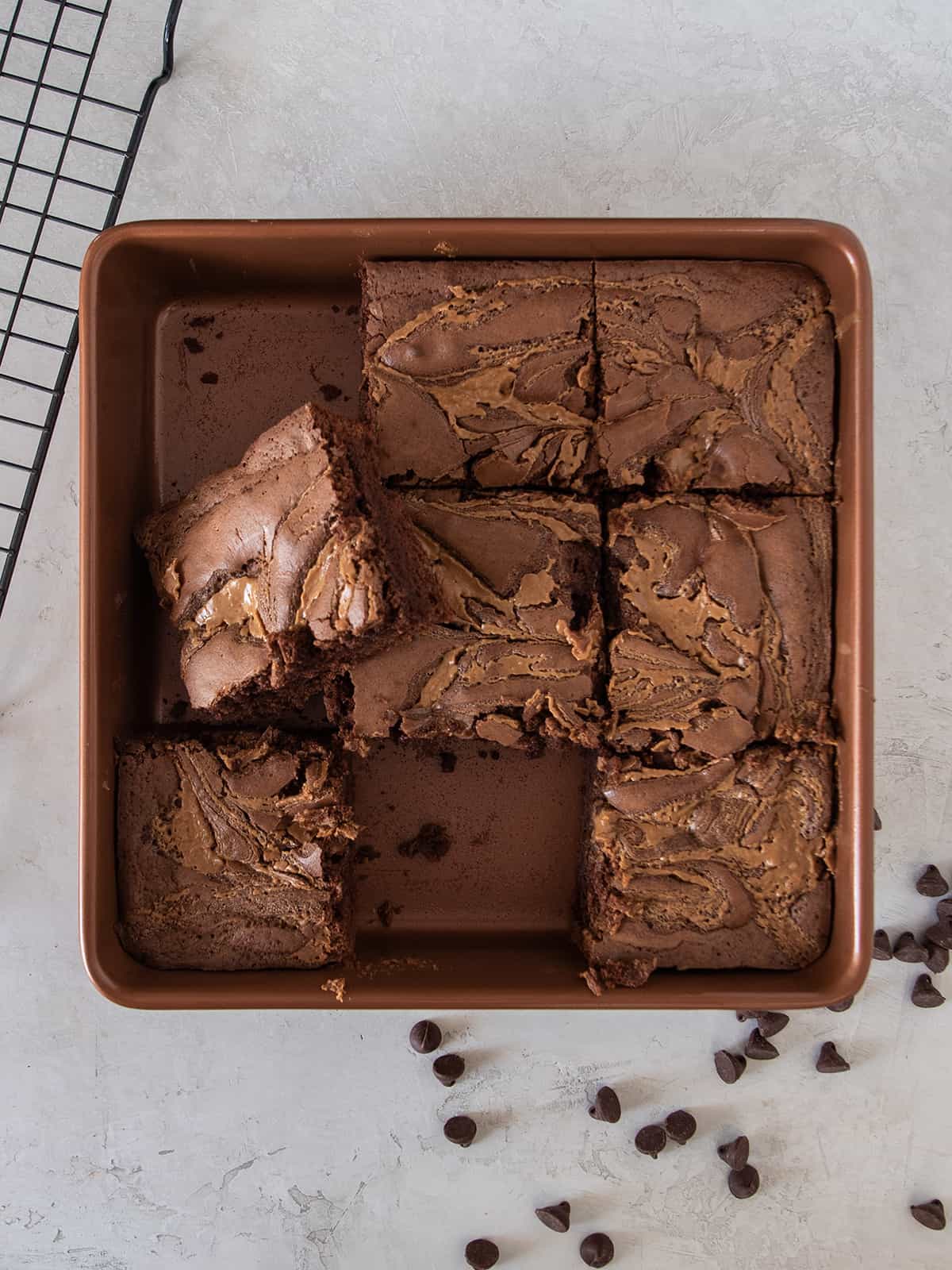 A tray of marbled peanut butter brownies with a brownie removed and another stacked on top.