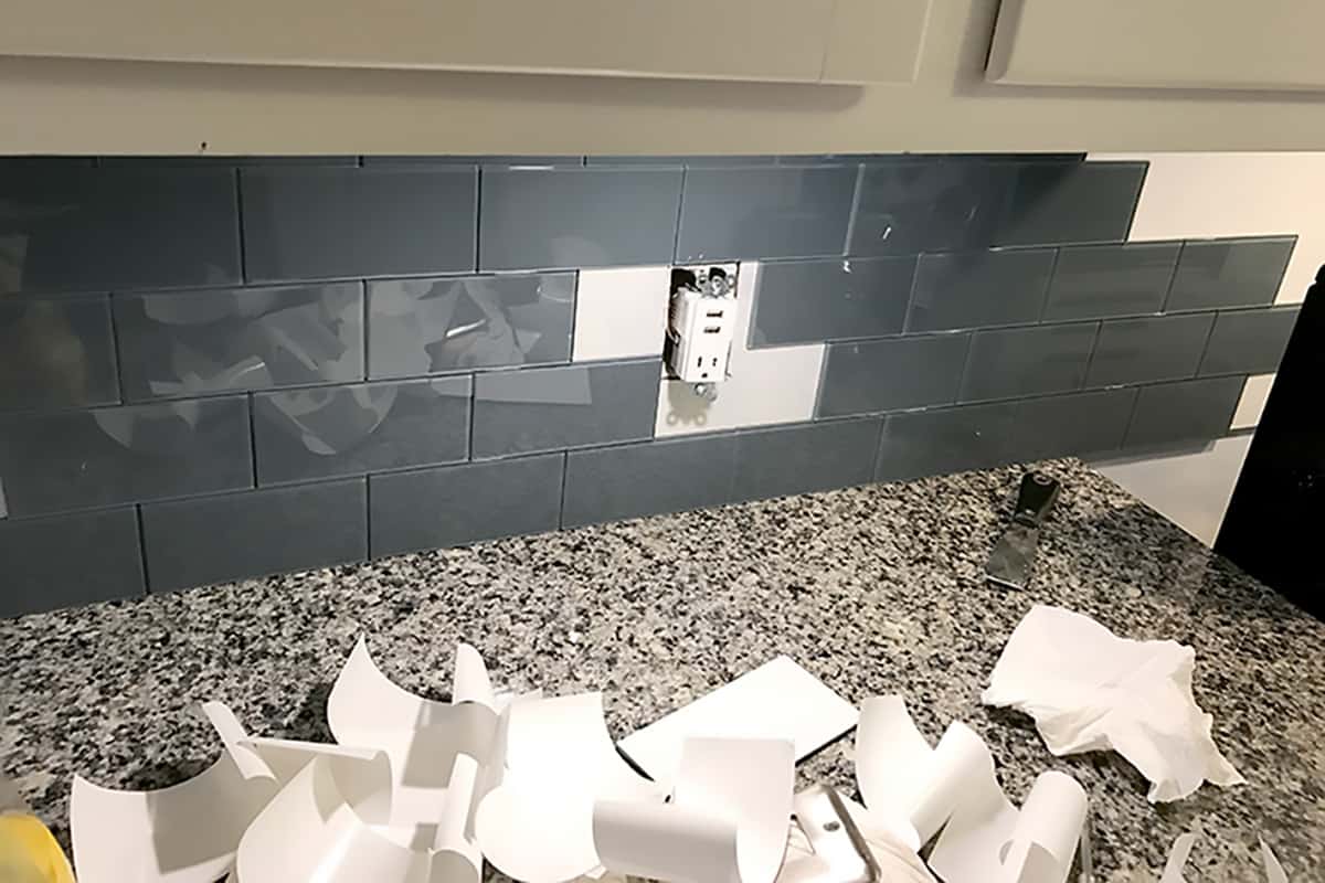 Peel and stick storm cloud glass tile applied above granite countertops.