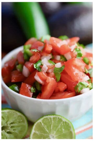 Small bowl of homemade pico de gallo with lime garnishes in front.