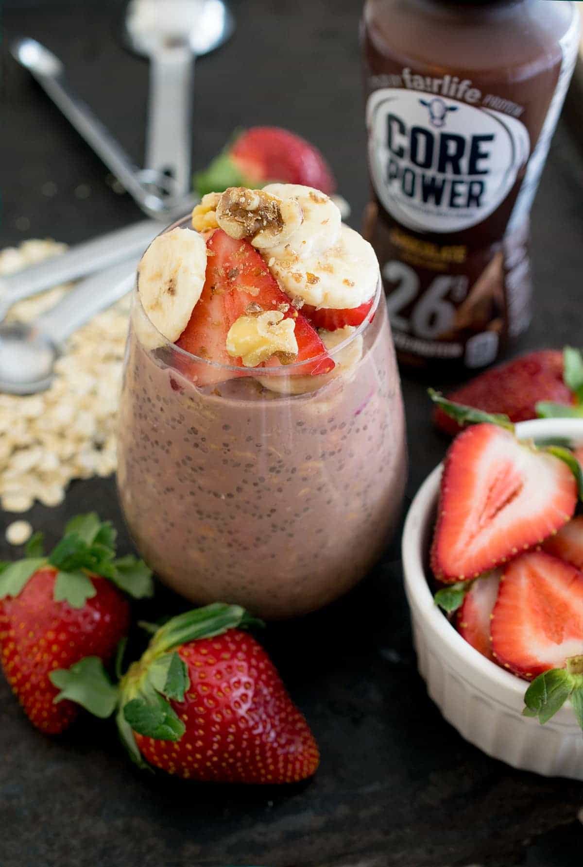 Chocolate Overnight Oats in a wine glass topped with strawberry slices, walnuts, and bananas.