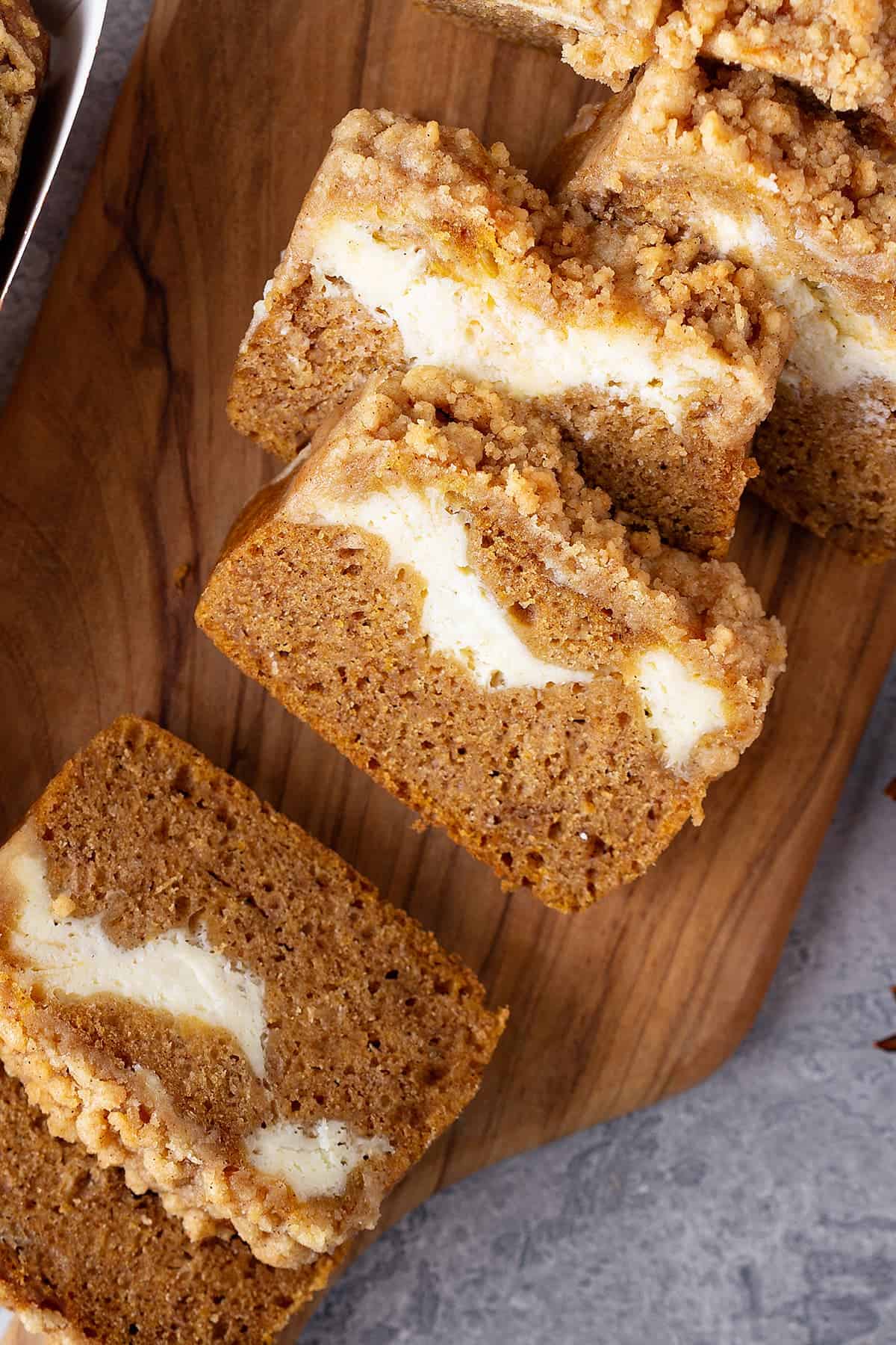 Pumpkin cream cheese swirl bread slices laid out on a table to show the cheesecake swirls and crumb topping.