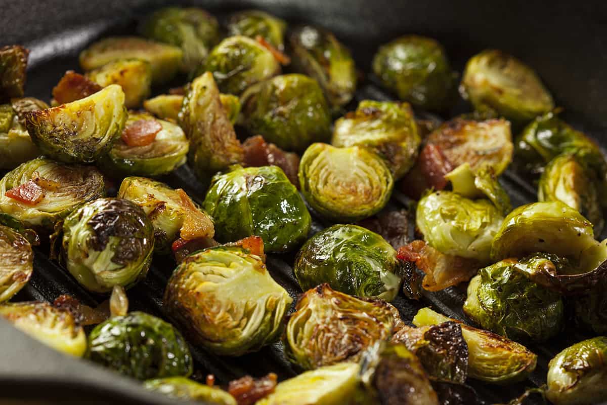 Horizontal view of Brussel sprouts with bacon and onions in a cast iron pan.