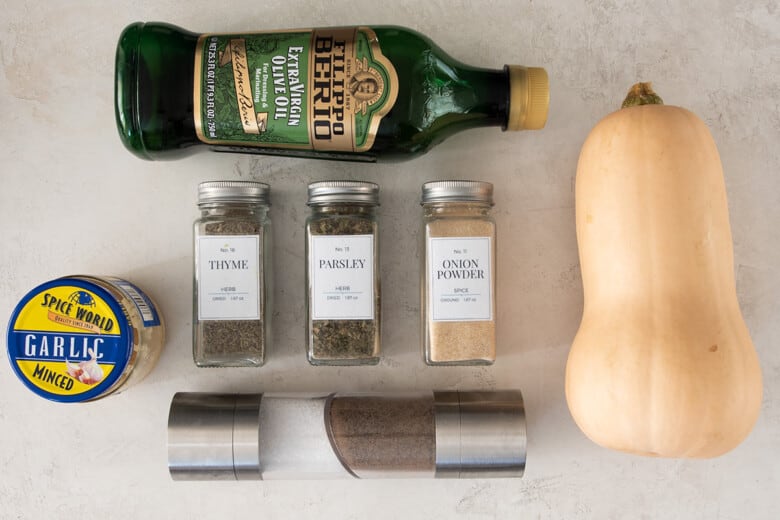Ingredients for oven roasted butternut squash including spices, olive oil, and a ripe squash.