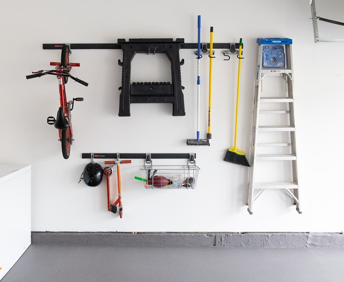Rubbermaid Garage FastTrack Wall Organizer with ladders, tools and toys hanging on wall.