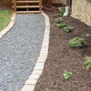 Gravel walkway path with flagstone border next to a small garden.