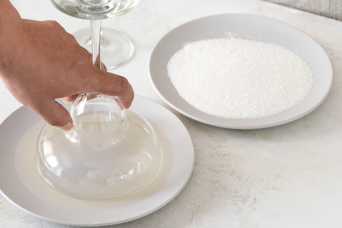 Demonstration of salt rimming a cocktail glass. A glass is dipped into a plate filled with lime juice while another plate is filled with kosher sea salt.