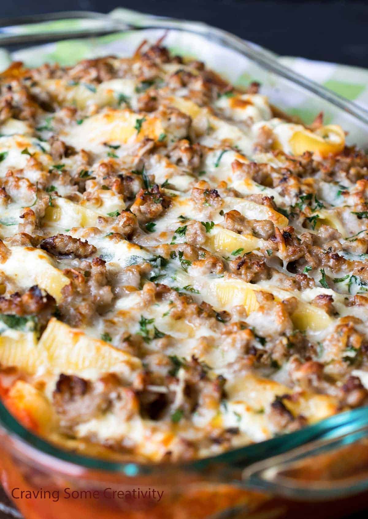 Baked Italian sausage stuffed pasta shells with ricotta and spinach in glass dish